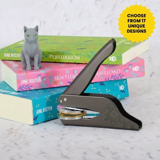 Custom library book embosser with a cat theme, displayed next to books and a cat figurine.
